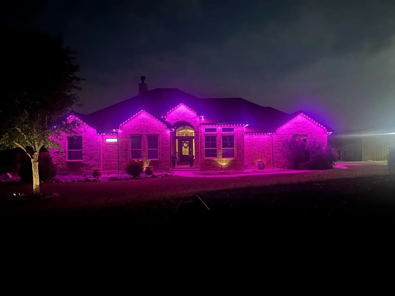Permanent JellyFish lighting by PLI illuminates a ranch home in magenta